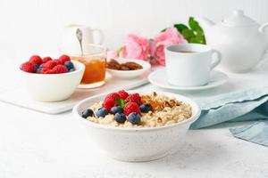 porridge di farina d'avena con mirtilli, lamponi, marmellata e noci, vista dall'alto. colazione con frutti di bosco foto