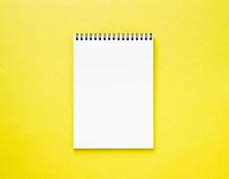 pagina bianca del blocco note in bianco sulla scrivania gialla, colore di sfondo. vista dall'alto, spazio vuoto per il testo. foto