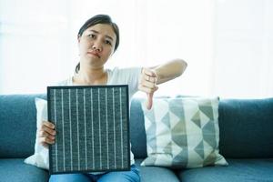 giovane donna asiatica che mostra un filtro purificatore d'aria usato e nuovo, confrontando tra filtro dell'aria nuovo e sporco usato. foto