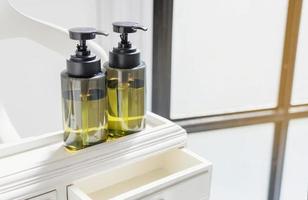 dispenser per flaconi a pompa per shampoo, balsamo, lozione, sapone su armadietto in legno foto