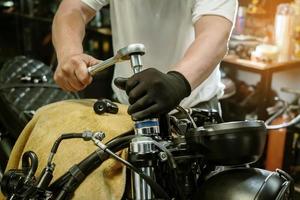 meccanico che utilizza una chiave inglese e una presa sulla motocicletta in garage .manutenzione, riparazione moto concetto .messa a fuoco selettiva foto