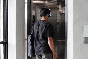 vista posteriore di giovani millenari che indossano abiti moderni che entrano nell'ascensore foto