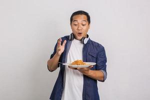 uomo asiatico che mangia spaghetti istantanei e si sente sorpreso da quanto sia delizioso foto