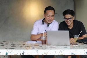 due studenti universitari asiatici che studiano insieme usando i computer portatili in un caffè