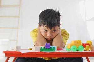 il ragazzo si sente annoiato e triste mentre gioca da solo a casa. esperienza traumatica infantile, psicologia, psicologia, sindrome di Asperger, disturbo di Asperger, autismo, autismo. foto