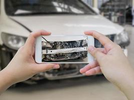 smartphone mobile della tenuta femminile che fotografa l'incidente d'auto foto