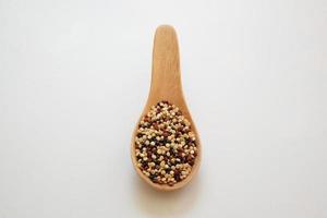 semi di quinoa nel cucchiaio di legno isolato su sfondo bianco. la quinoa è una buona fonte di proteine per le persone che seguono una dieta a base vegetale. foto