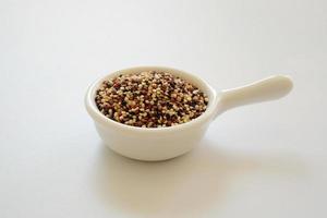 semi di quinoa nella tazza bianca isolata su sfondo bianco. la quinoa è una buona fonte di proteine per le persone che seguono una dieta a base vegetale.