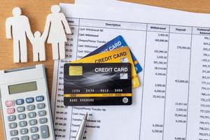 modello di famiglia e calcolatrice su estratto conto e carta di credito su un tavolo di legno. foto