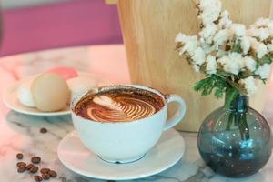 tazza di caffè latte art sul tavolo di vetro. sfondo sfocato di riflessione foglia. foto