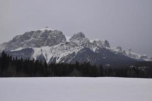 montagne rocciose innevate con lago ghiacciato in primo piano foto