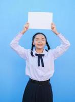 ragazza della scuola che tiene cartellone su sfondo blu. foto