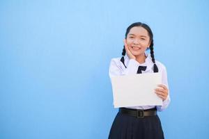 ragazza della scuola che tiene cartellone su sfondo blu. foto