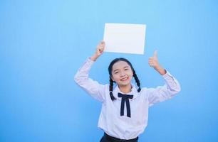 ragazza della scuola che tiene cartellone su sfondo blu. foto