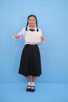 ragazza della scuola che tiene cartellone su sfondo blu. foto