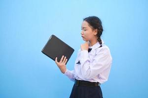 ragazza della scuola che tiene compressa su sfondo blu. foto