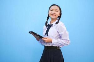 ragazza della scuola che tiene compressa su sfondo blu. foto