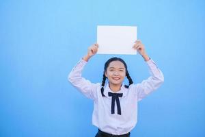 ragazza della scuola che tiene cartellone su sfondo blu. foto