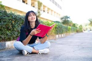 studentessa con zaino rosa seduto a terra con sfondo scolastico. foto