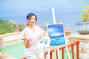 giovane ragazza che utilizza un'immagine di disegno a pennello su carta tela, in una splendida vista del paesaggio a koh tao thailand. foto