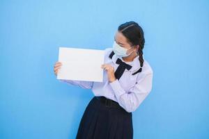 la ragazza della scuola mostra il tabellone per le affissioni su fondo blu. foto