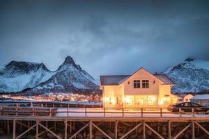 casa scandinava illuminata sul villaggio norvegese che brilla con la montagna di picco foto