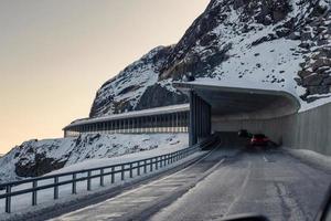 strada del tunnel con l'auto che guida attraverso la montagna della neve sull'inverno alle isole lofoten foto