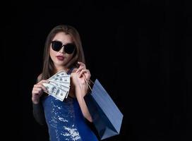 una bella donna asiatica con un vestito blu è contenta dopo aver ricevuto soldi per fare shopping foto