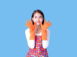 una bella donna asiatica sorride e alza la mano, fingendo di pulire la casa foto