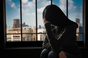donna sedersi depressione in piedi vicino alla finestra foto
