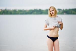 ritratto di un modello alto dall'aspetto fantastico che indossa t-shirt e bikini che cammina nel lago. foto