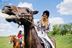 trainare giovani belle ragazze a cavallo su un campo in una giornata di sole foto