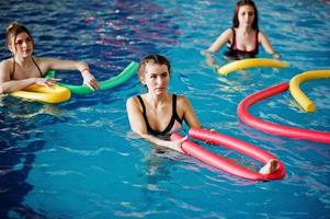 gruppo fitness di ragazze che fanno esercizi aerobici in piscina al parco acquatico. attività sportive e ricreative. foto