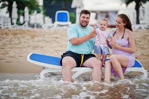 vacanze estive. genitori e persone attività all'aperto con i bambini. buone vacanze in famiglia. padre, madre incinta, figlia seduta sul lettino al mare spiaggia di sabbia. foto
