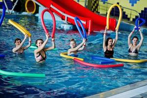 gruppo fitness di ragazze che fanno esercizi aerobici in piscina al parco acquatico. attività sportive e ricreative. foto