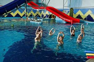 gruppo fitness di ragazze che fanno esercizi aerobici in piscina al parco acquatico. attività sportive e ricreative. foto