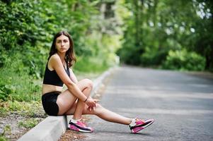 ragazza sportiva in abbigliamento sportivo che riposa in un parco verde dopo l'allenamento in natura. uno stile di vita sano. foto