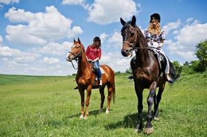 trainare giovani belle ragazze a cavallo su un campo in una giornata di sole foto