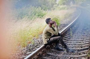 fresco nero africano americano uomo seduto e in posa sulla ferrovia in campagna. foto