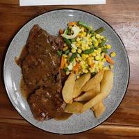 porzione deliziosa e succosa di bistecca di filetto alla griglia servita con pomodoro e patate e altre verdure grigliate su un piatto bianco foto