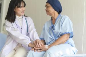 medico che tiene la mano del malato di cancro anziano in ospedale, assistenza sanitaria e concetto medico foto