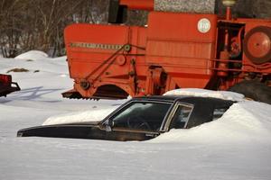 vecchia macchina ricoperta di neve vicino a mietitrebbia foto