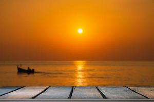 tavolo di legno vuoto sul bellissimo tramonto sfocato sul mare foto