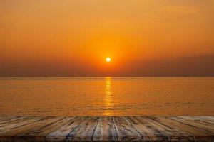 tavolo di legno vuoto sul bellissimo tramonto sfocato sul mare foto