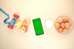 smart phone con schermo vuoto, uova, latte e mandorle in tavola foto