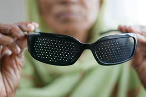 donne anziane in possesso di occhiali di perforazione con fori per la visione di allenamento foto