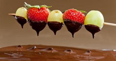 frutta immerso nella fonduta di cioccolato foto