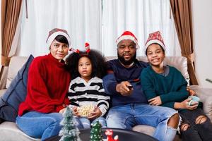 famiglia afroamericana in tema natalizio. la famiglia felice si diverte a sedersi insieme sul divano di casa. foto