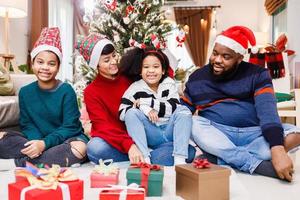 famiglia afroamericana in tema natalizio. felice famiglia afroamericana di quattro persone che si uniscono insieme sul pavimento foto