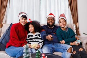 famiglia afroamericana in tema natalizio. la famiglia felice si diverte a sedersi insieme sul divano di casa. foto